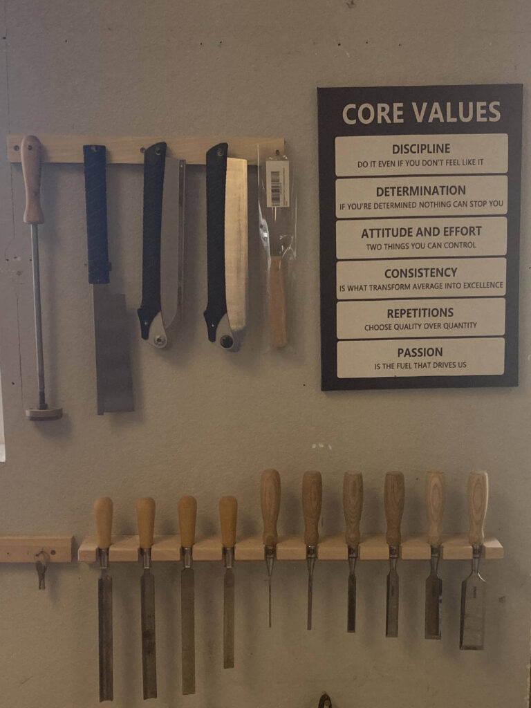 plaque on wall lists out core values next to hand carpenter tools arranged by size.